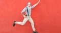 Senior crazy man jumping and listening music outdoor with red wall in background - Happy mature male celebrating and dancing