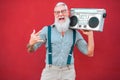 Senior crazy man with 80`s boombox stereo playing rock music with red background - Trendy mature guy having fun dancing with