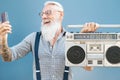 Senior crazy man using phone while listening music with vintage boombox - Hipster guy having fun using mobile smartphone