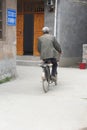 Senior cyclist cycles in the rustic ancient village of Daxu, China