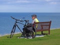 Senior cyclist on coastal bench