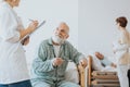 Senior doctor in a beige uniform talks to an elderly patient during a walk around hospital