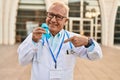 Senior doctor with grey hair holding blue ribbon pointing finger to one self smiling happy and proud Royalty Free Stock Photo