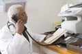 Senior Doctor Holding Document While Using Landline Phone