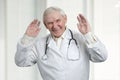 Senior doctor laughing hard with raised hands up.