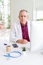 Senior doctor man at the clinic concentrated working with computer looking for a cure Royalty Free Stock Photo