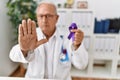 Senior doctor man holding purple ribbon awareness with open hand doing stop sign with serious and confident expression, defense Royalty Free Stock Photo