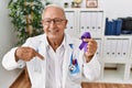 Senior doctor man holding purple ribbon awareness pointing finger to one self smiling happy and proud Royalty Free Stock Photo