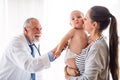 Senior doctor, mother and a baby boy in an office. Royalty Free Stock Photo