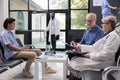 Senior doctor standing beside elderly patient discussing health care treatment during checkup visit Royalty Free Stock Photo