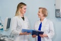 Senior doctor talking with young woman assistant standing in the gynecological office with chair and lamp on the Royalty Free Stock Photo