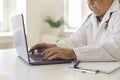 Senior doctor using laptop, giving online consultations to patients or entering data into system Royalty Free Stock Photo