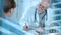 Senior doctor writing prescription to his patient; light effect; multiple exposure Royalty Free Stock Photo
