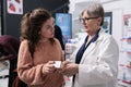 Senior drugstore employee helping woman client with spf medical leaflet