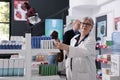 Senior drugstore worker looking at pills packages checking pharmacy shelves