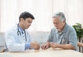 Senior elder asian man asking young caucasian doctor about indications and contraindications of new medicine, healthcare and Royalty Free Stock Photo