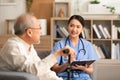 Senior elder man patient talking to caring female doctor physician at nursing home in hospital . Asain doctor explaining well- Royalty Free Stock Photo