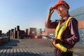 A senior elderly Asian worker engineer wearing safety vest and helmet standing and holding digital tablet at shipping cargo