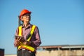 A senior elderly Asian worker engineer wearing safety vest and helmet standing and holding digital tablet at shipping cargo