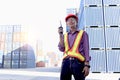 A senior elderly Asian worker engineer wearing safety vest and helmet standing and holding radio walkies talkie at logistic