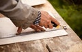 Senior elderly carpenter using a straightedge to draw a line on a board