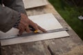 Senior elderly carpenter using a straightedge to draw a line on a board