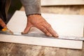 Senior elderly carpenter using a straightedge to draw a line on a board