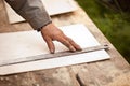 Senior elderly carpenter using a straightedge to draw a line on a board