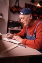 Senior elderly Carpenter writing project notes in woodwork workshop. Profession and small business concept Royalty Free Stock Photo