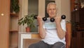 Senior elderly caucasian man doing weight lifting dumbbell exercising at home