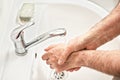 Senior elderly man his hands and wrist with soap under tap water faucet, detail photo. Can be used as hygiene illustration concept