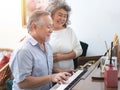 Senior elderly man plays piano in nursing home listened to by elderly woman,Retreatment elderly asian grandmother and grandfather Royalty Free Stock Photo