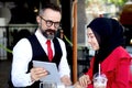 Senior elderly mature business man using tablet and discussing with headscarf hijab Muslim women together during having a coffee Royalty Free Stock Photo