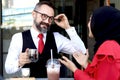 Senior elderly mature business man having a coffee at outdoor coffee shop and talking with headscarf hijab Muslim women, happy Royalty Free Stock Photo
