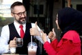 Senior elderly mature business man talking and give thumbs up with hijab Muslim women during having a coffee at outdoor cafe, Royalty Free Stock Photo