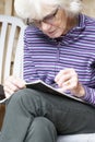 Senior elderly person keeping mind active by doing crossword puzzle