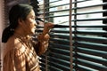 Senior Elderly woman look at window in evening. Grandmother wait patiently for home coming person with sad lonely depress. Asian