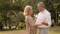 Senior elegant caucasian couple dancing looking at each other feeling love and cherish on their anniversary in the park with copy Royalty Free Stock Photo