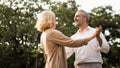 Senior elegant caucasian couple dancing looking at each other feeling love and cherish on their anniversary in the park with copy Royalty Free Stock Photo