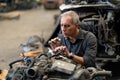 Senior engineer checking old used car engine in machinery parts shop warehouse. old technician man Repair vehicle automobile