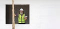 Senior engineer in hardhat and safety vest holding tablet computer stand in a window opening. Working atmosphere at construction Royalty Free Stock Photo