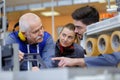 senior engineer instructing apprentice at machine bench