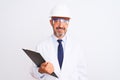 Senior engineer man wearing helmet glasses holding clipboard over isolated white background with a confident expression on smart Royalty Free Stock Photo
