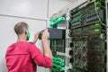 Senior Engineer takes the server out of the rack with computer equipment. The man performs repair and maintenance of the servers Royalty Free Stock Photo