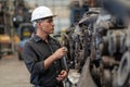 Senior engineer using laptop computer checking list old used car engine in machinery parts shop warehouse. old technician man Royalty Free Stock Photo