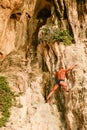 A senior man free solo climber hangs on the cliff of Rai Leh