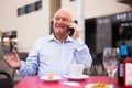 Old man having telephone conversation in outdoor cafe Royalty Free Stock Photo