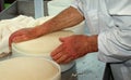 Senior expert cheesemaker checks he wheel of cheese just made in