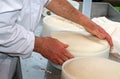 Senior expert cheesemaker checks he wheel of cheese just made in