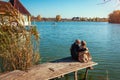 Senior family couple relaxing by autumn lake. Happy man and woman enjoying nature and hugging sitting on pier Royalty Free Stock Photo